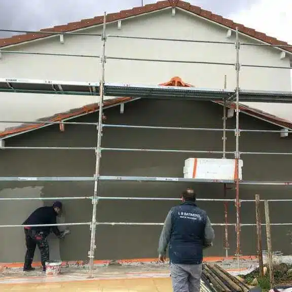 Application d’un enduit sur une façade de maison dans le cadre de travaux d’entretien et de rénovation extérieure.