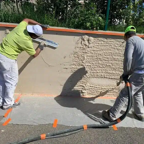 Travaux de pose d’enduit projeté sur une façade, réalisés par des artisans spécialisés en rénovation extérieure. 